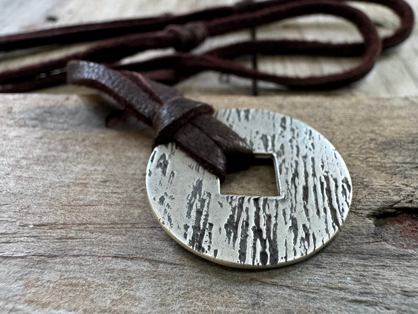 Rustic silver wood grain pendant on adjustable leather lace