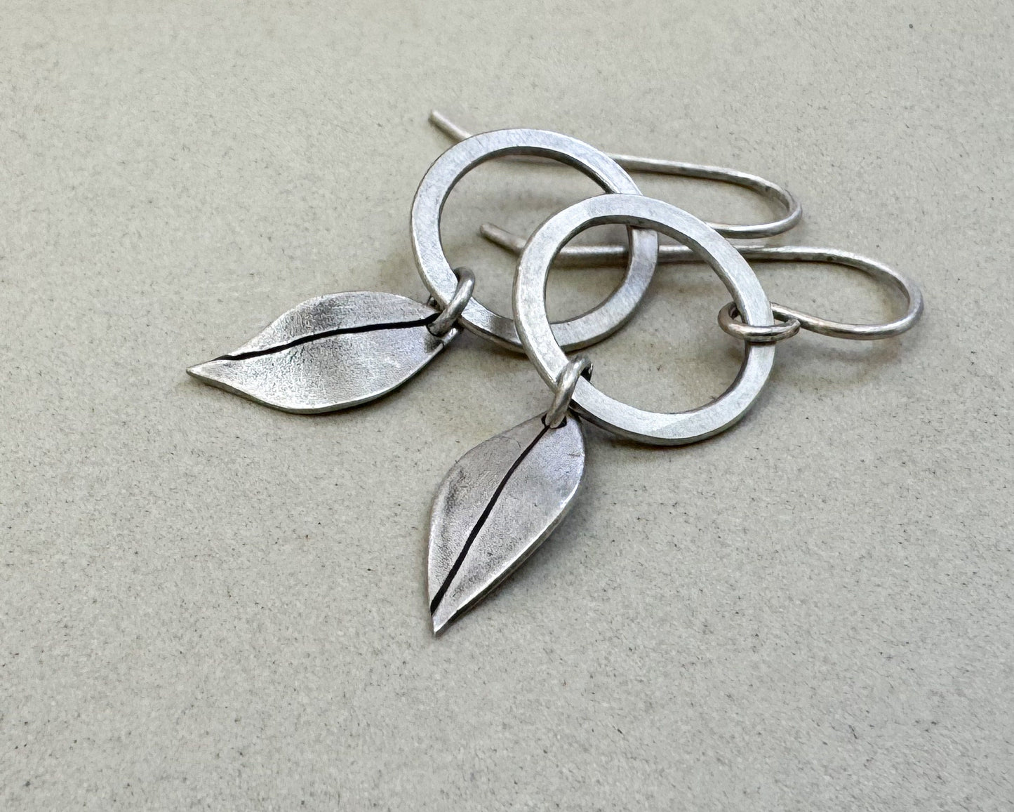 Little silver hoops with simple leaves in a brushed satin finish