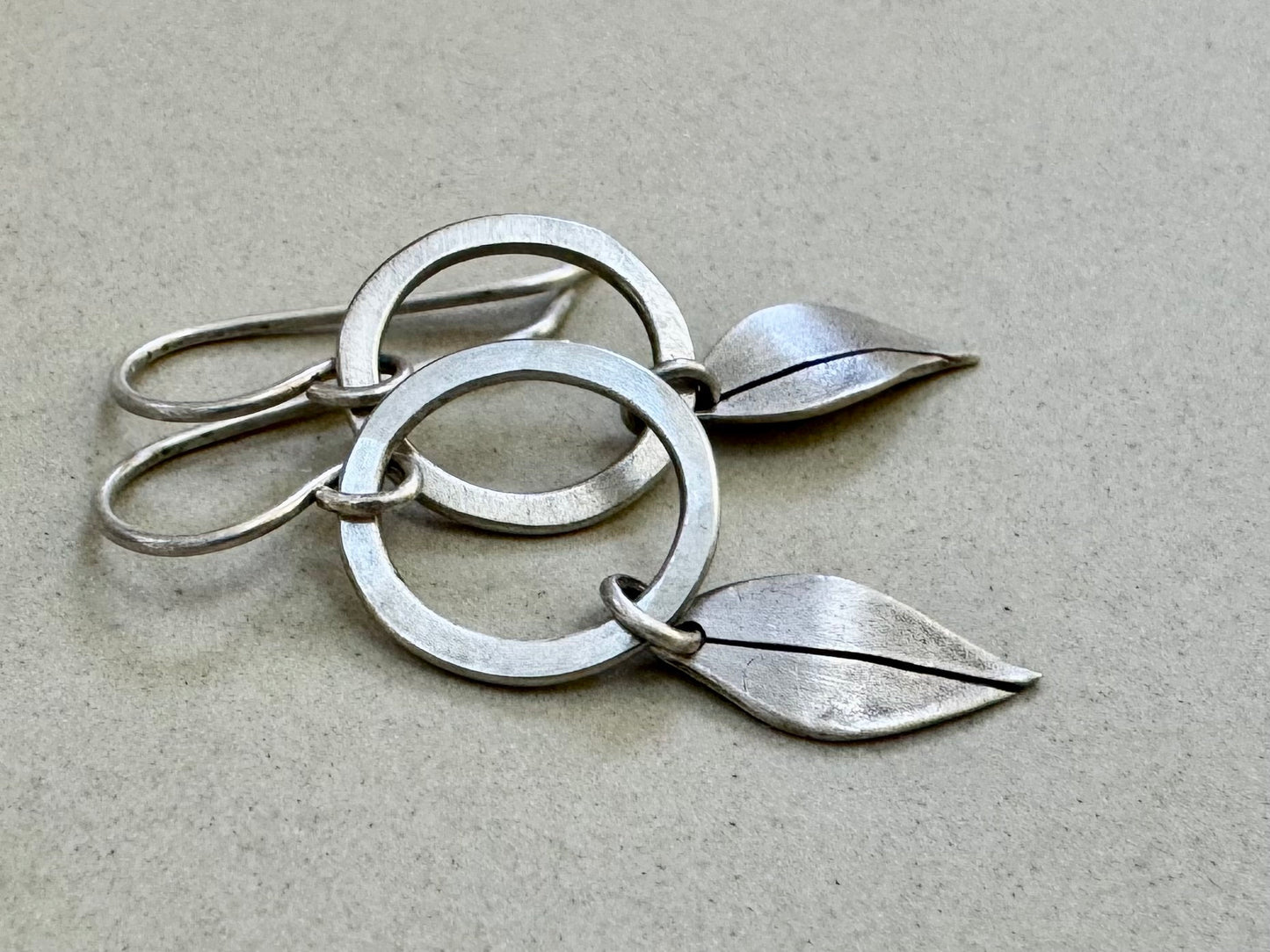 Little silver hoops with simple leaves in a brushed satin finish