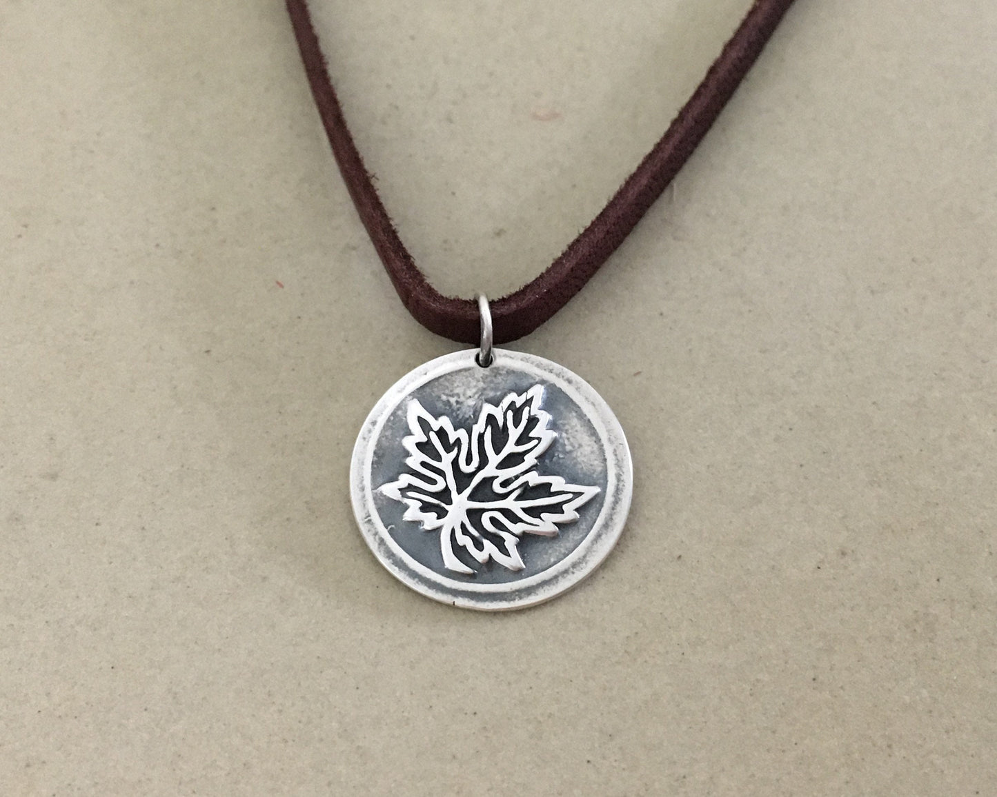 Silver maple leaf pendant on leather