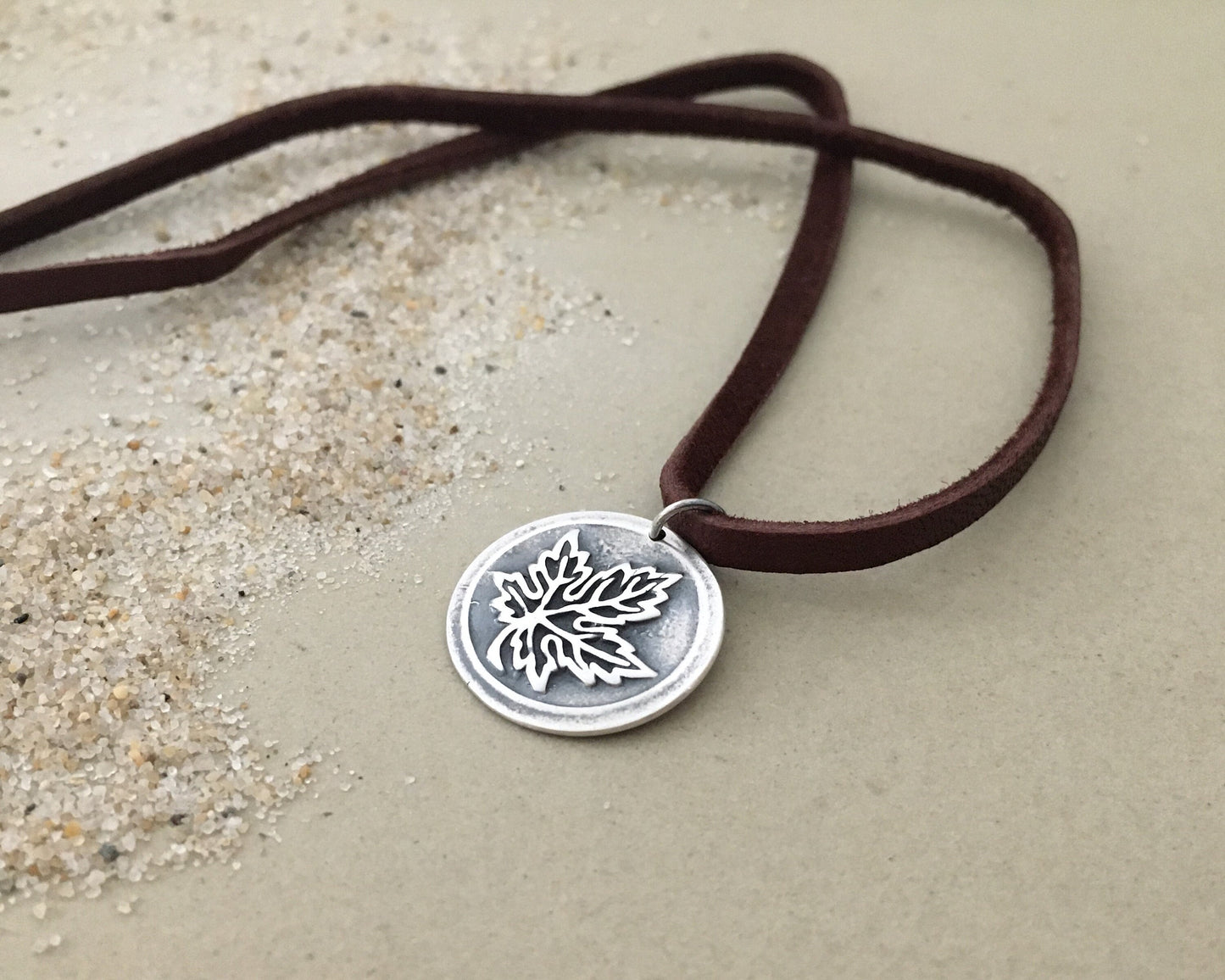 Silver maple leaf pendant on leather