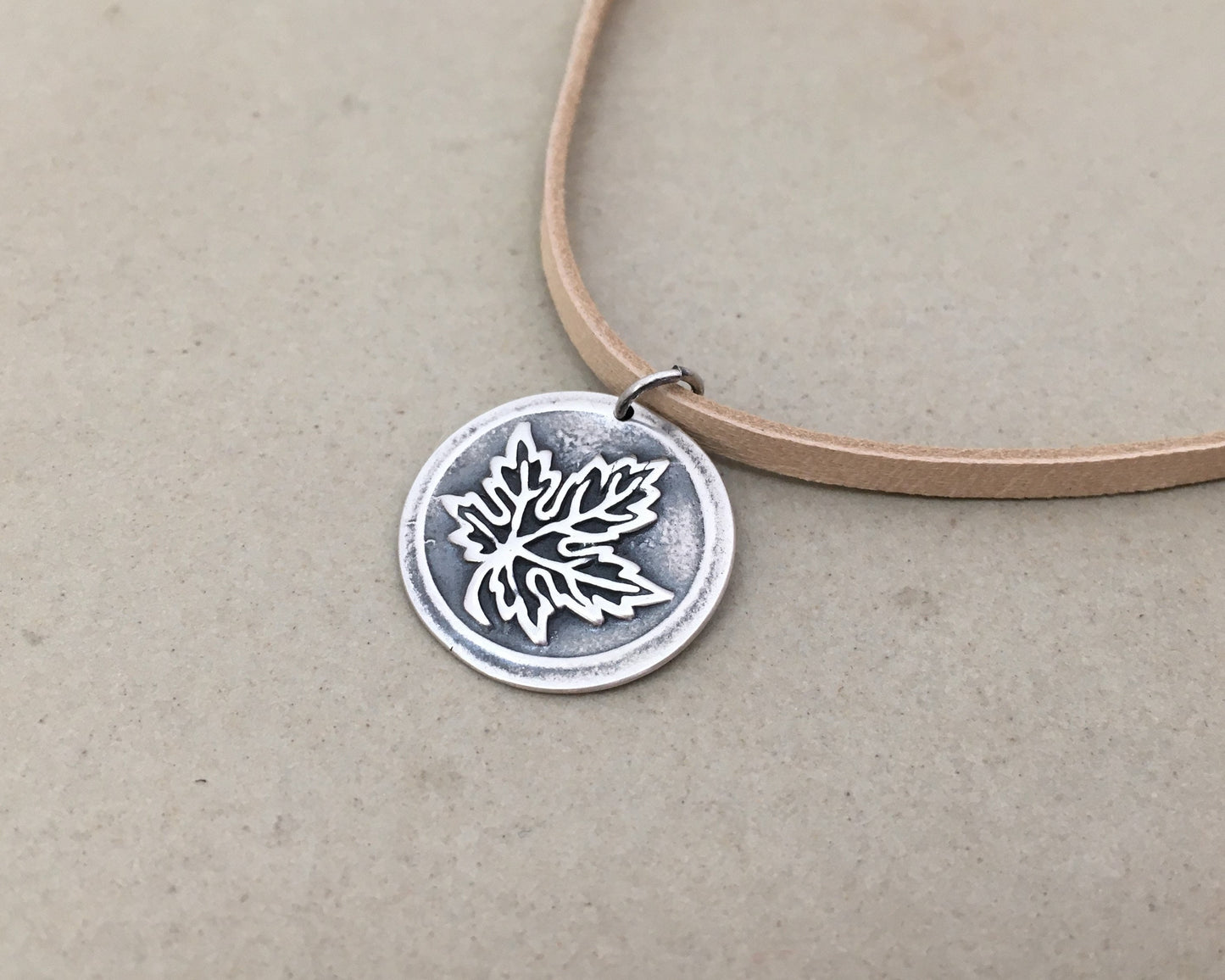 Silver maple leaf pendant on leather